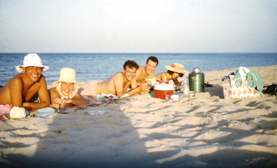 A lively group enjoying a sunny beach picnic with smiles and laughter all around.