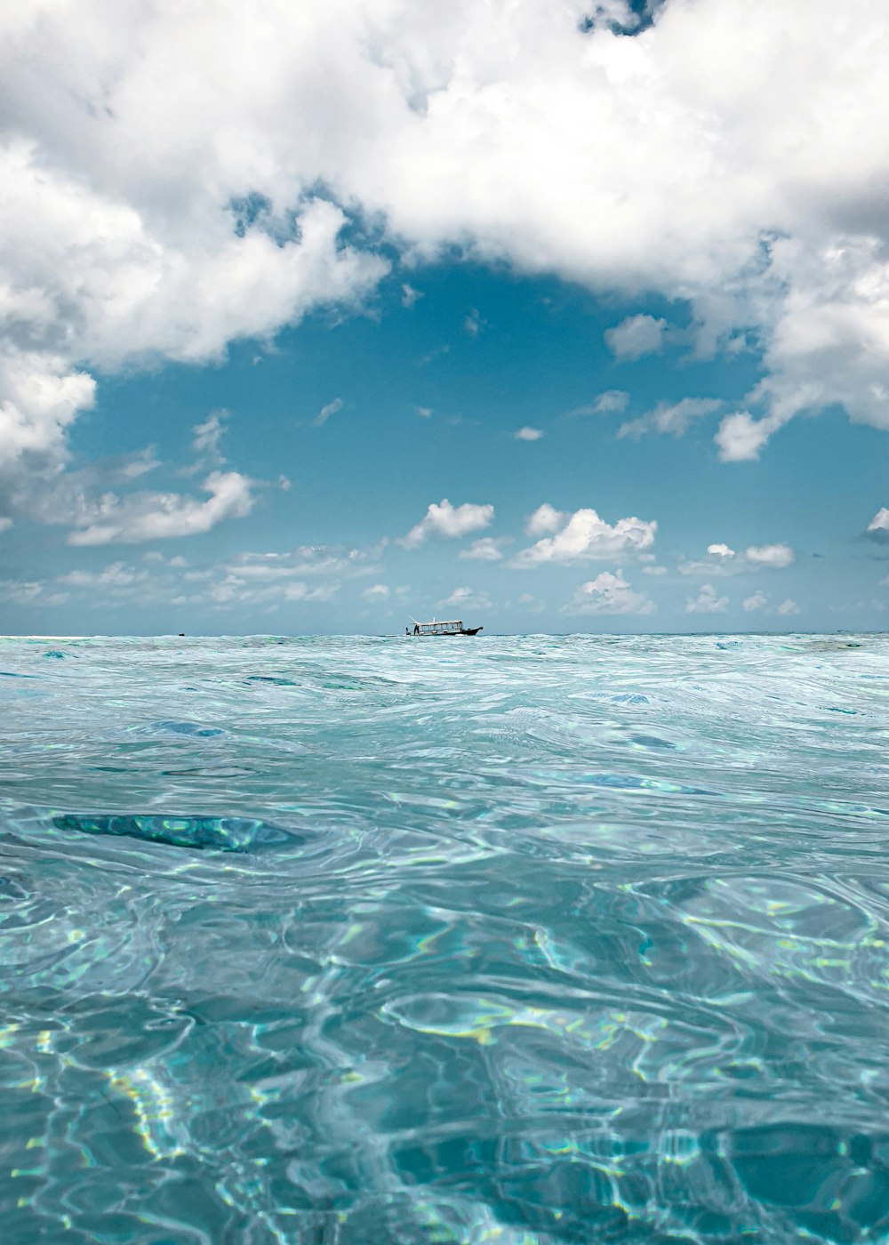 white boat on sea under blue sky and white clouds during daytime