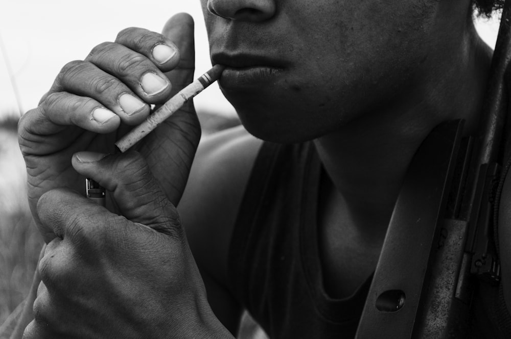 man smoking cigarette in grayscale photography