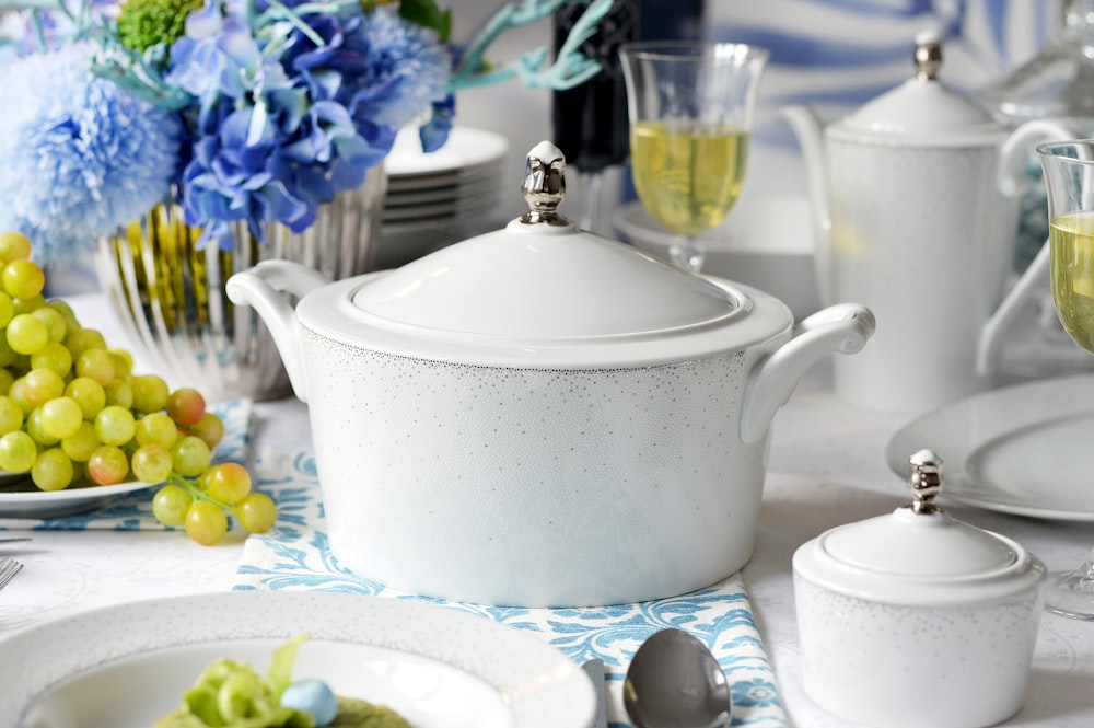 white ceramic bowl with lid on white and blue floral table cloth