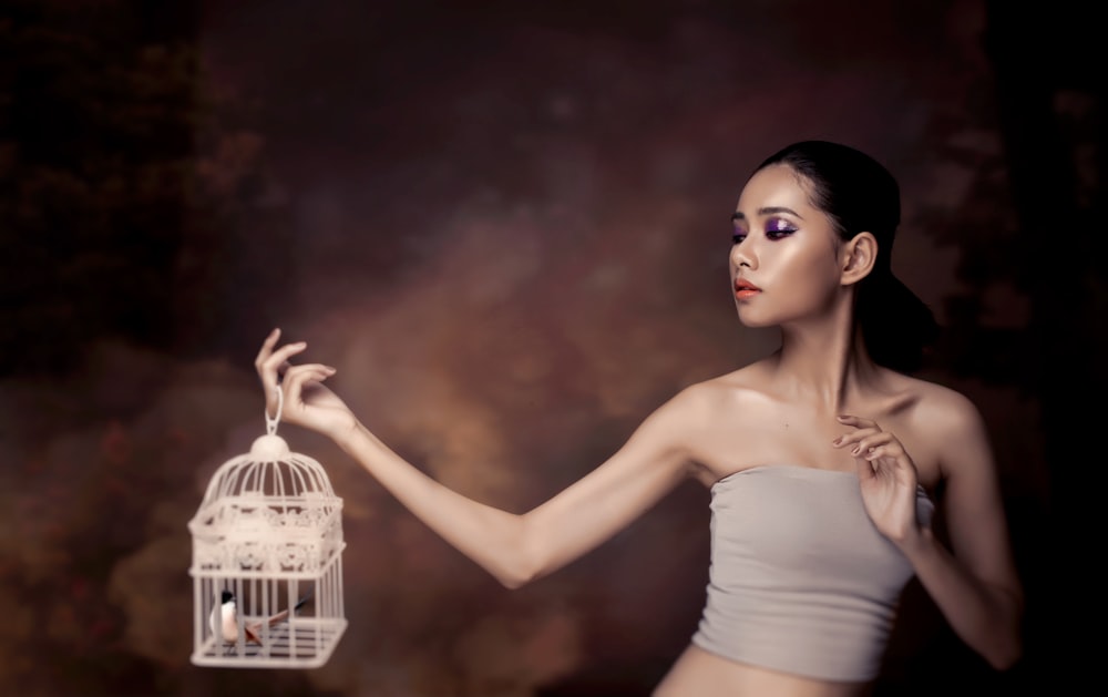 woman in white tank top holding white bird cage