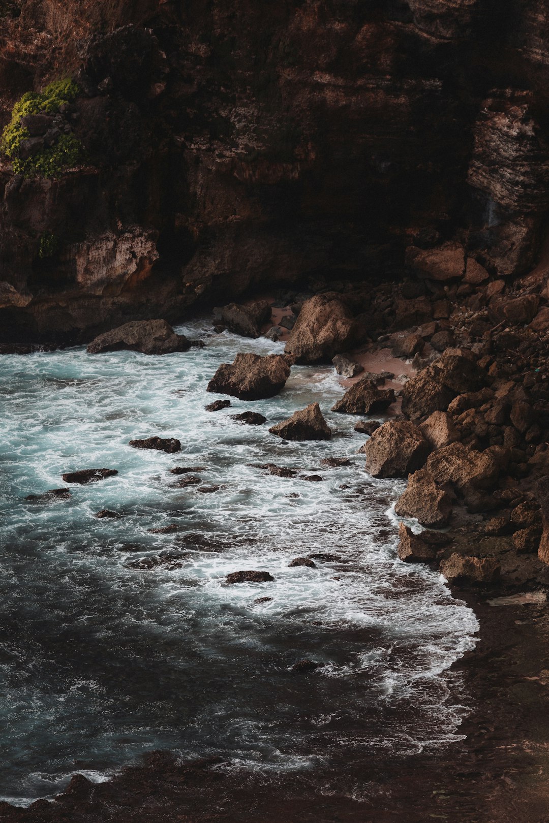 brown rocky mountain beside body of water during daytime