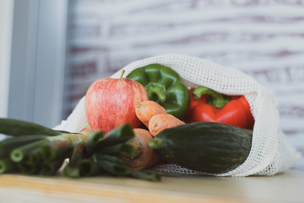 red tomato beside green vegetable on white table