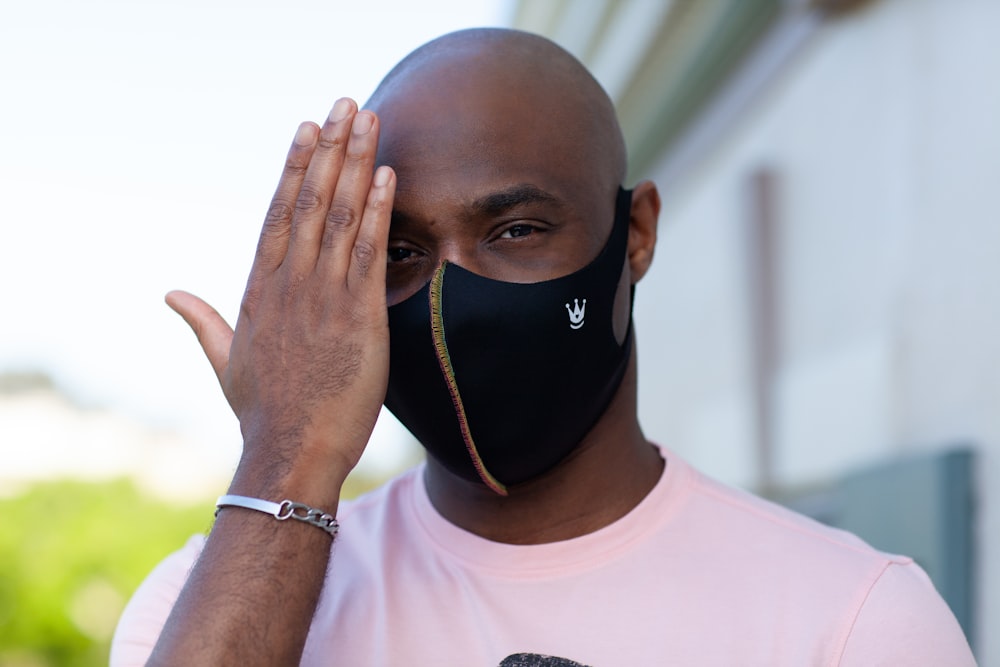 man in white crew neck shirt covering his face with black and white nike face mask
