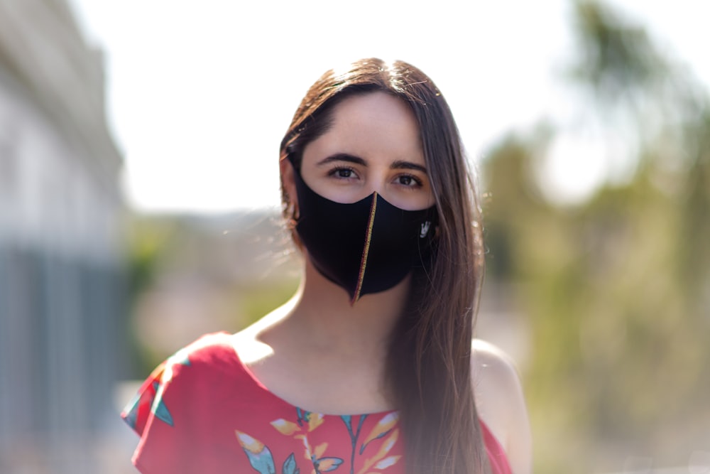 woman in white and red floral shirt with black mask