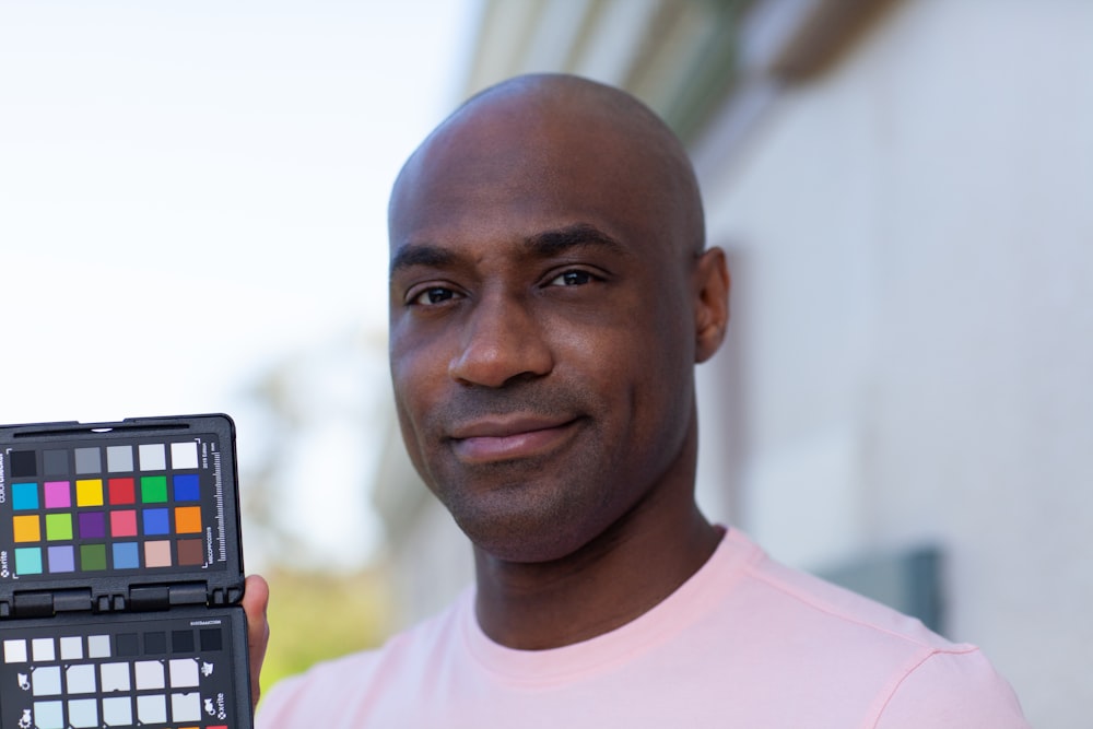 man in pink crew neck shirt holding black and gray camera