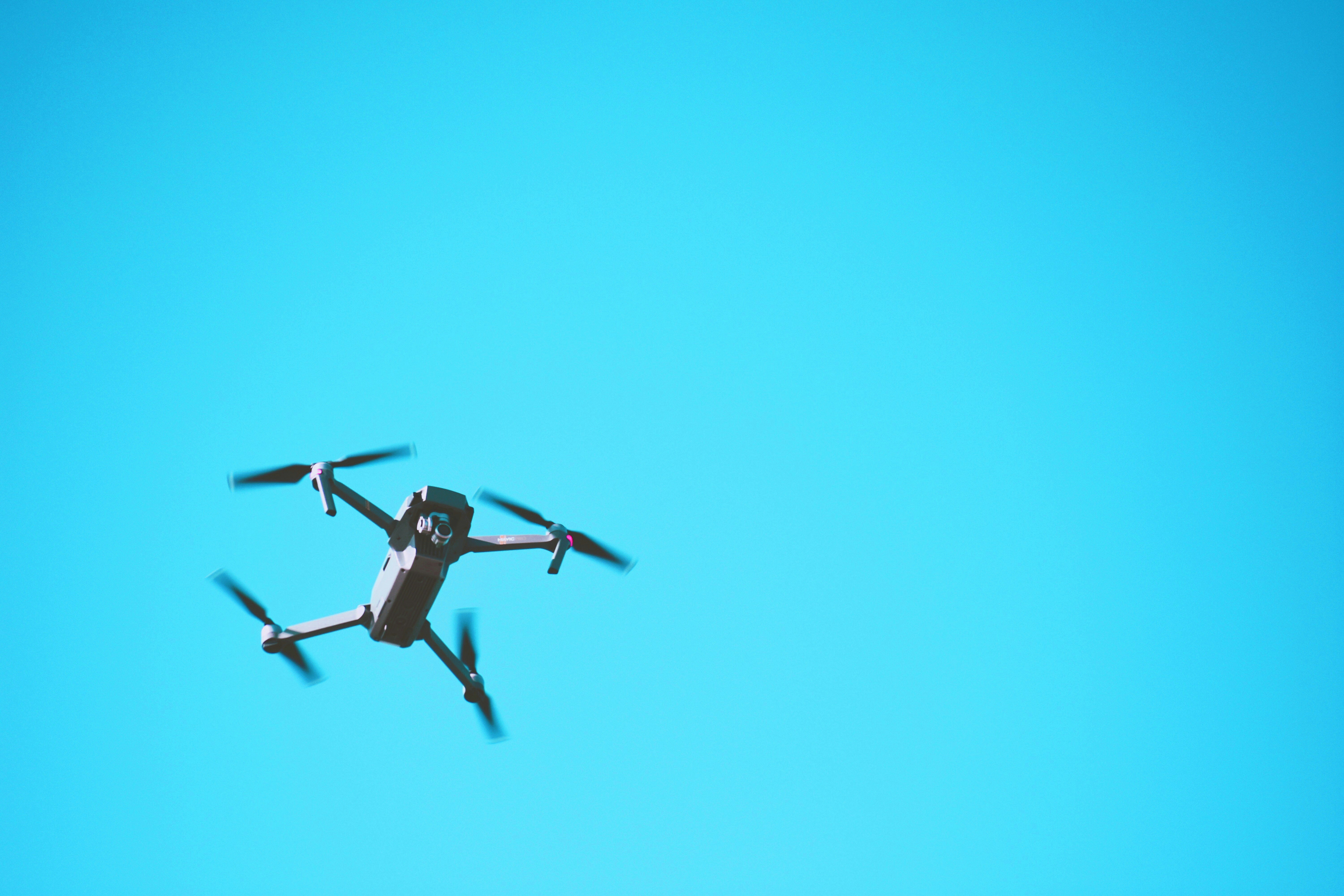 black drone flying in the sky