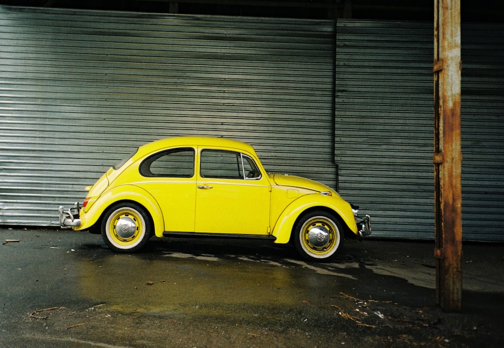 yellow volkswagen beetle parked beside gray roll up door