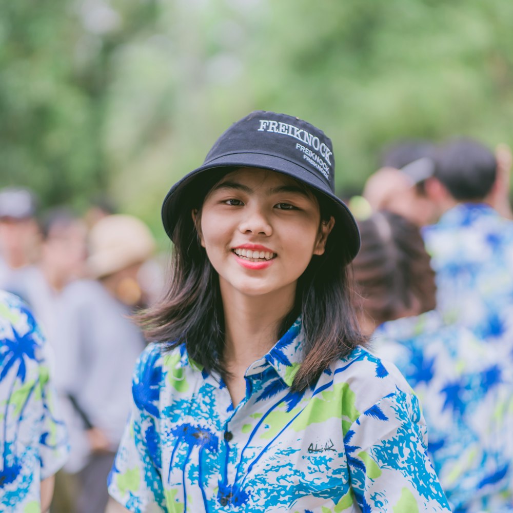 woman in blue green and yellow floral button up shirt wearing black hat