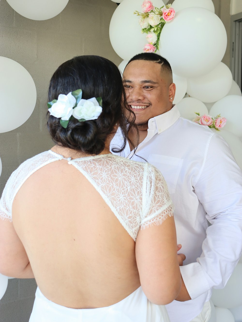 man in white dress shirt hugging woman in white sleeveless dress