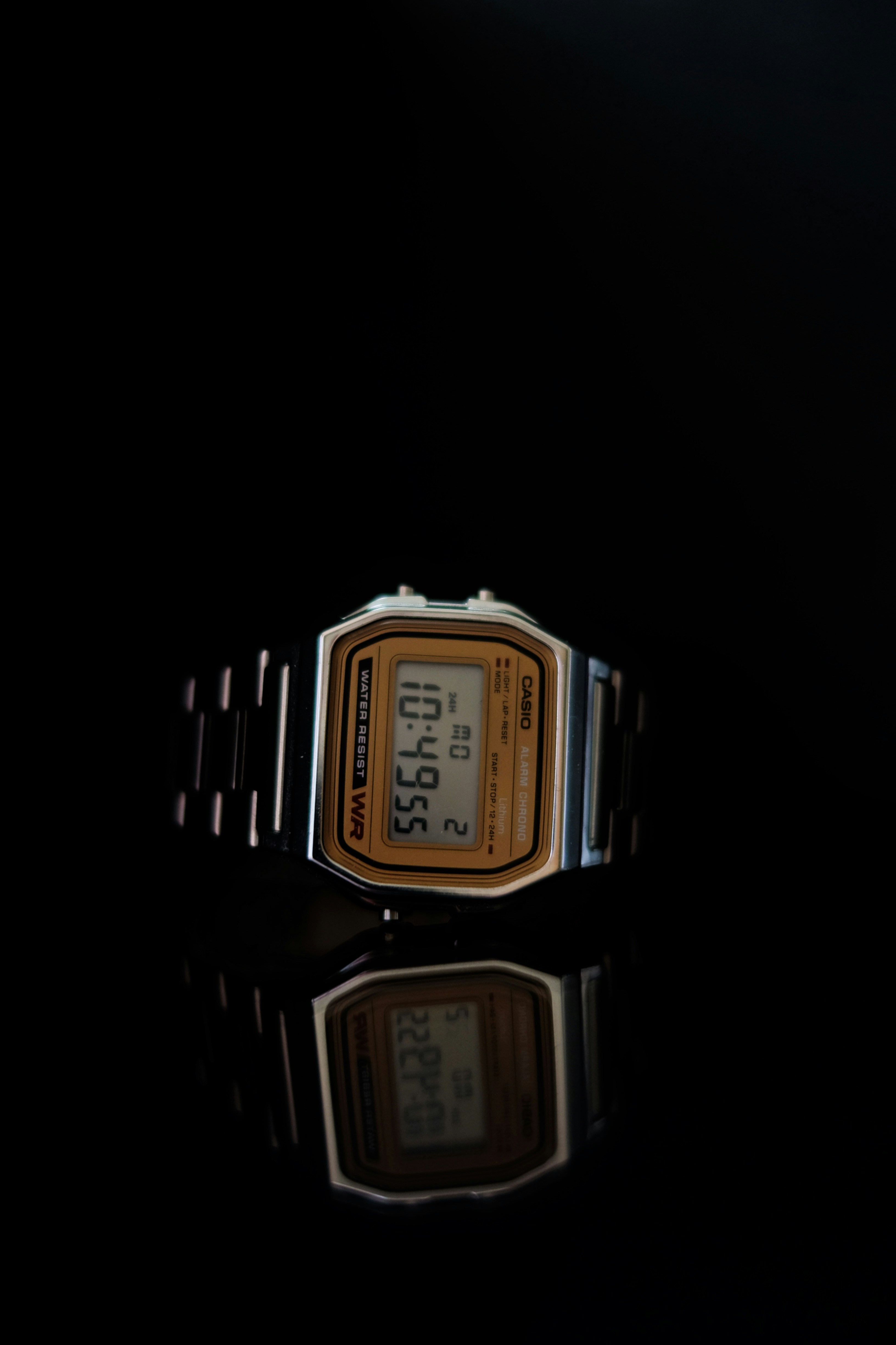 A digital watch with a metallic band on black surface
