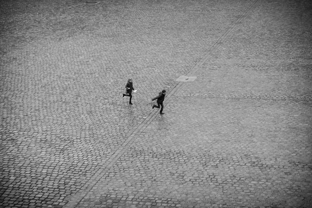 2 personnes marchant sur un trottoir en béton gris