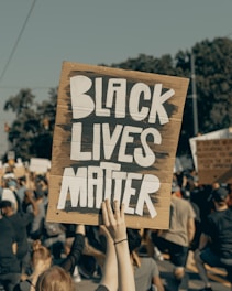 person holding brown wooden signage