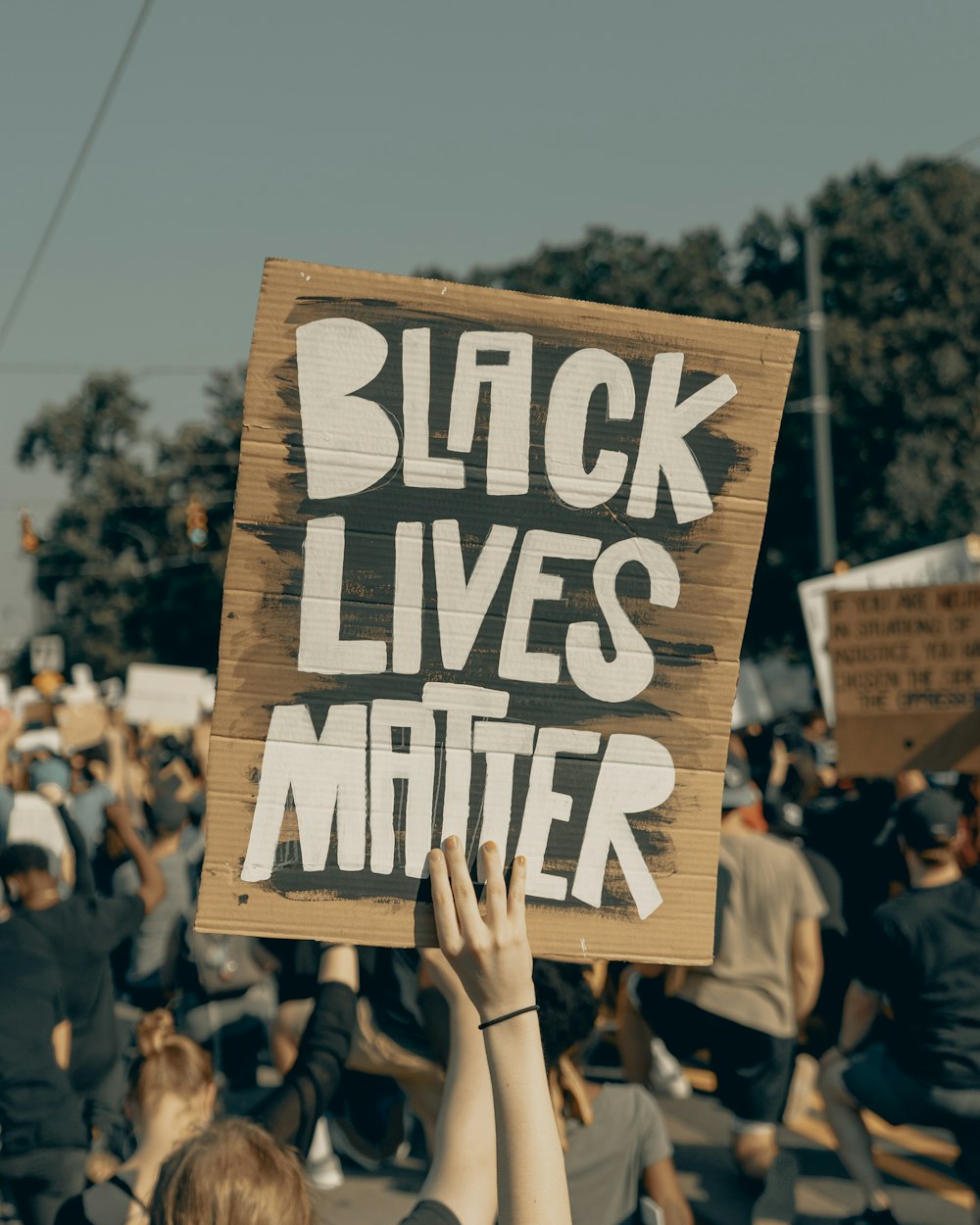 person holding brown wooden signage