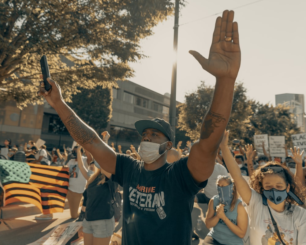 man in black and white crew neck t-shirt raising his hands