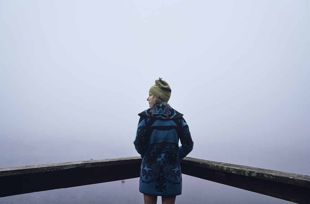 woman in blue and white floral dress standing on bridge during daytime