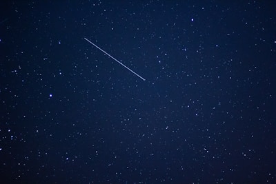 A close-up of a starry sky with a shooting star in motion.