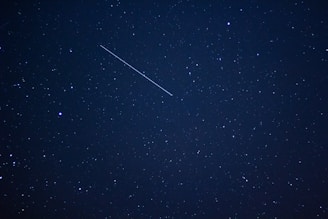 A close-up of a starry sky with a shooting star in motion.