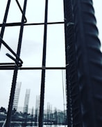 Metal rebar structures stand vertically, forming a framework against a pale sky. In the background, additional rebar formations are visible, likely part of a construction site. The image conveys a sense of industrial progress and development.