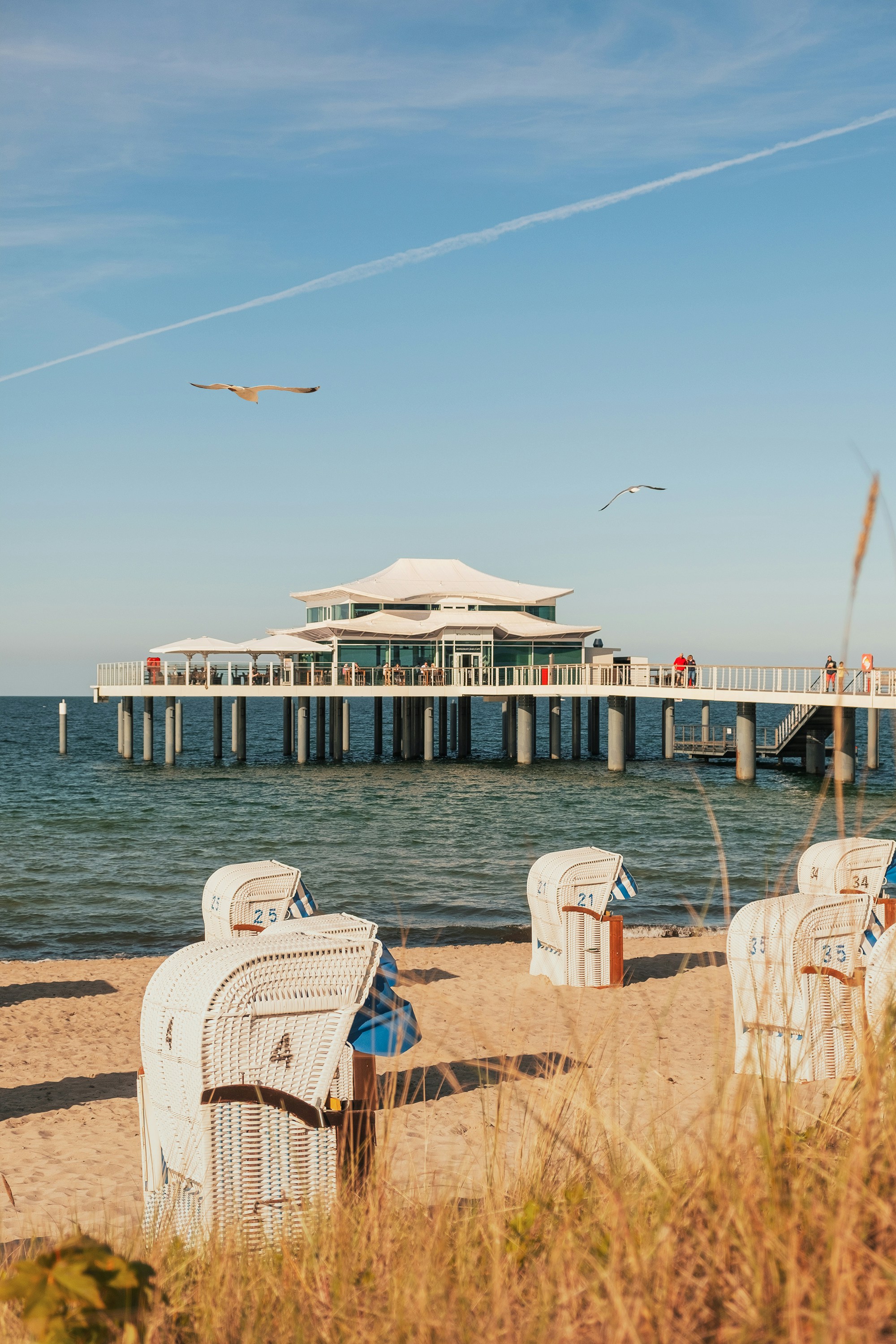 Weiße und braune Strandliegen aus Holz tagsüber am Strandufer Foto