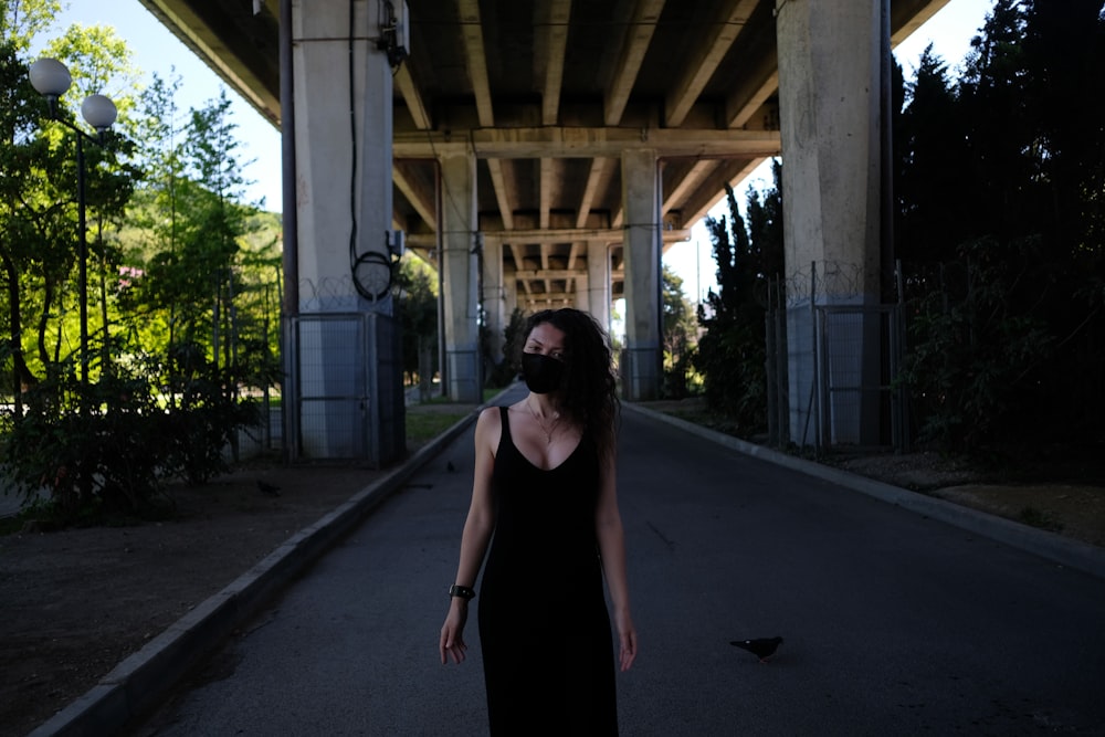 woman in black tank dress standing on gray concrete floor during daytime