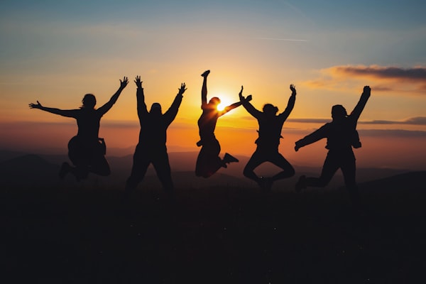 People jumping in sillhoette with a sunset in the background.