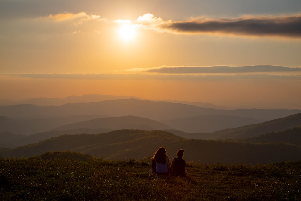 2 person sitting on green grass field during daytime