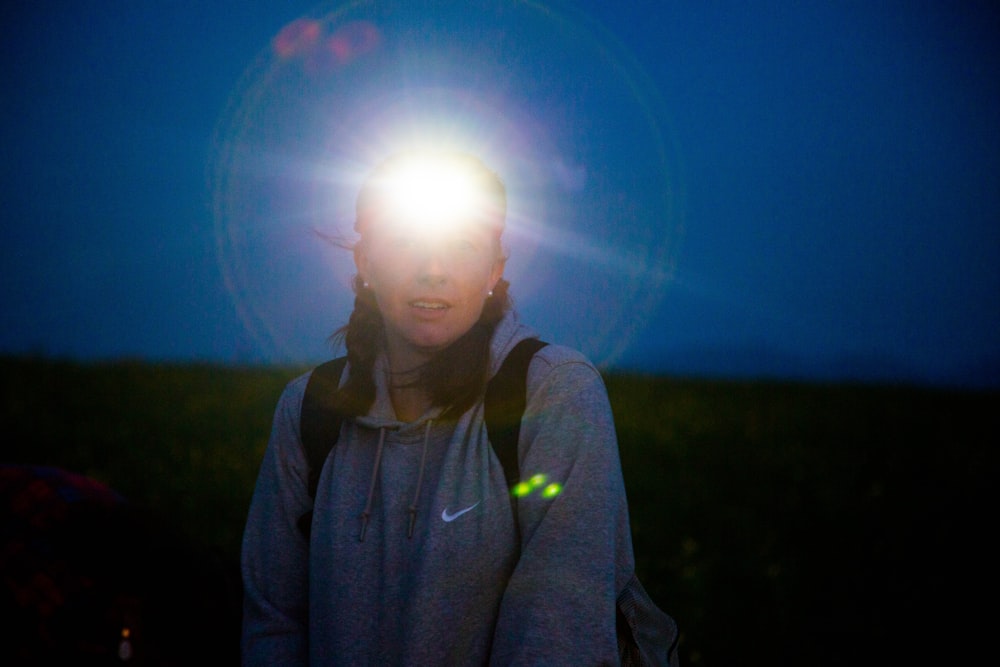 woman in gray hoodie standing on green grass field during daytime