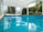 A tranquil swimming pool surrounded by lush greenery and clear water.