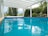 A tranquil swimming pool surrounded by lush greenery and clear water.