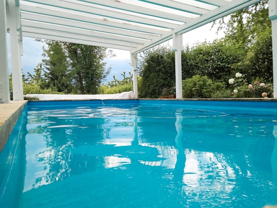 A serene swimming pool surrounded by lush greenery and modern water filtration equipment.