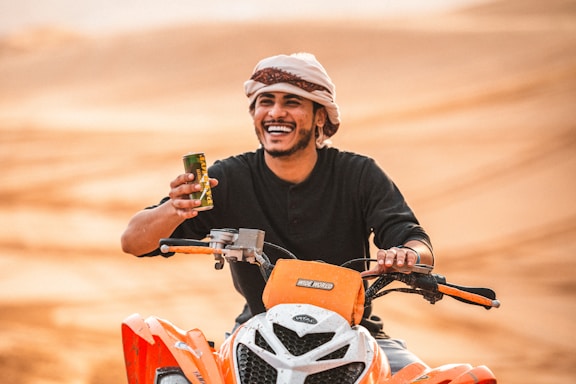 man in black crew neck shirt wearing white and orange helmet riding orange and black motorcycle