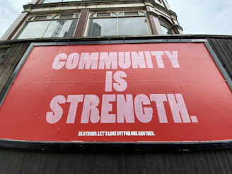 A large red billboard with white text reading COMMUNITY IS STRENGTH on a building