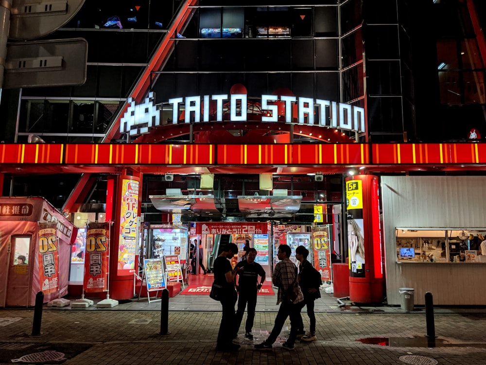 people walking on sidewalk near red and white store during night time