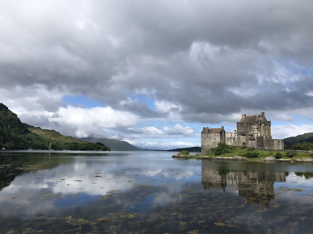 gray concrete castle on body of water under cloudy sky during daytime