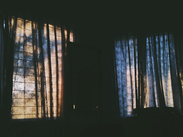 Soft natural light filtering through delicate white curtains in a peaceful memorial room.