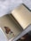 An open book is placed on a marble surface, displaying a butterfly resting on a flower. The left page features a detailed image of an orange and black butterfly on a light purple flower. The right page contains text in Portuguese, written in two different fonts.
