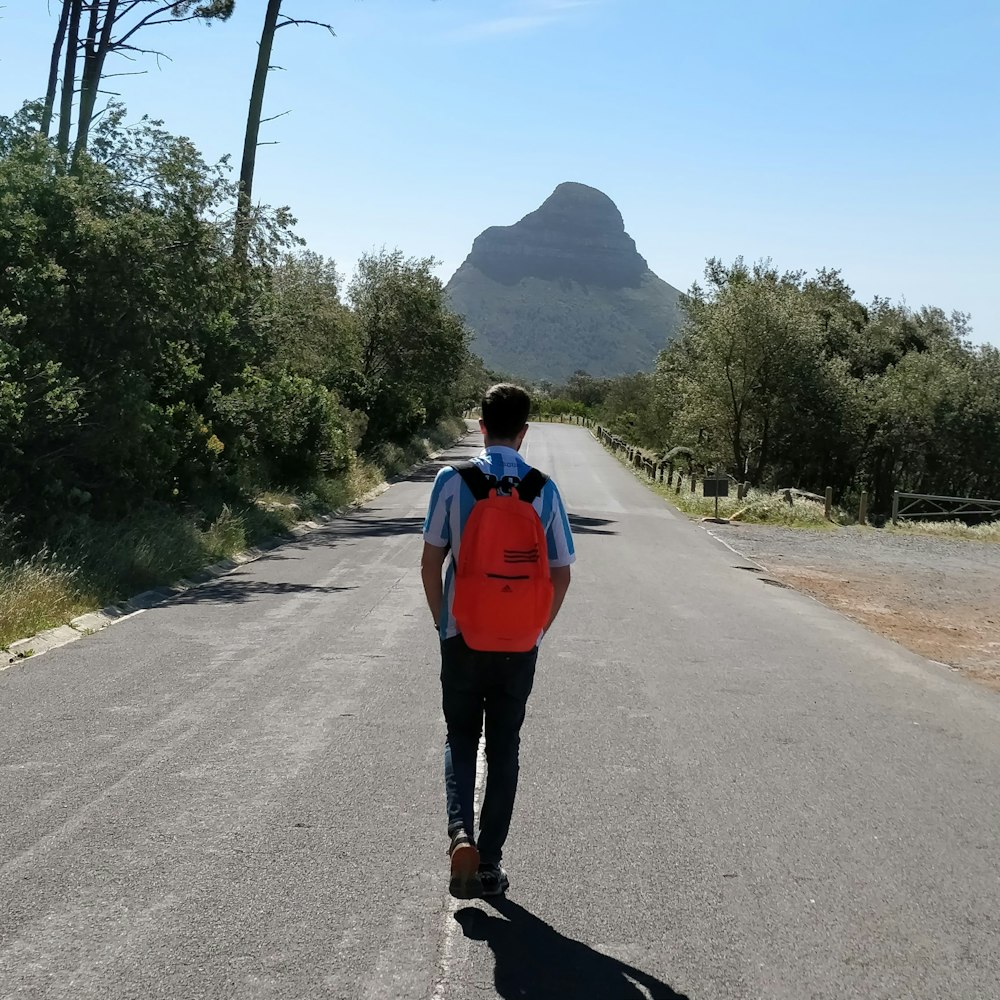 woman in red jacket standing on road during daytime