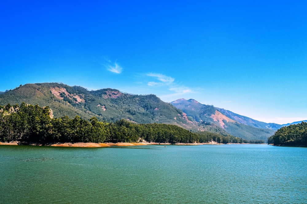 green and brown mountains beside blue sea under blue sky during daytime