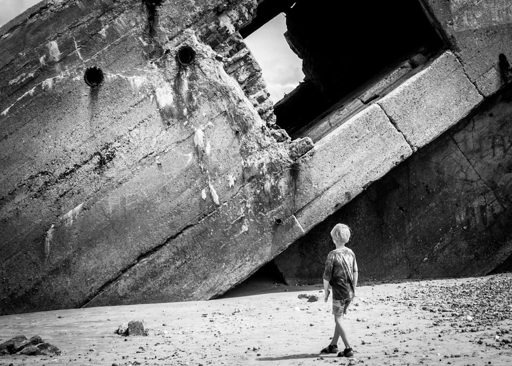 grayscale photo of man walking on beach