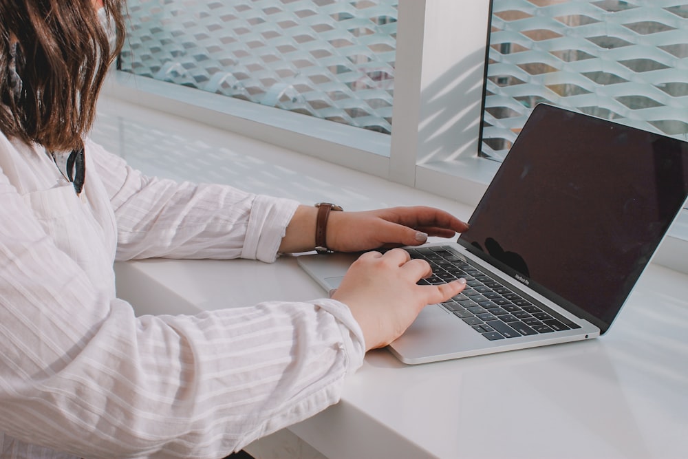 person in white long sleeve shirt using macbook pro