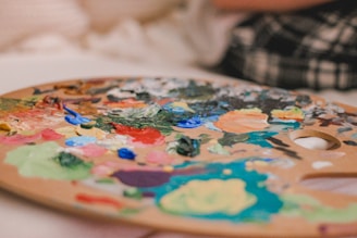 An artist's palette with vibrant colors and unique materials like coffee and wine.