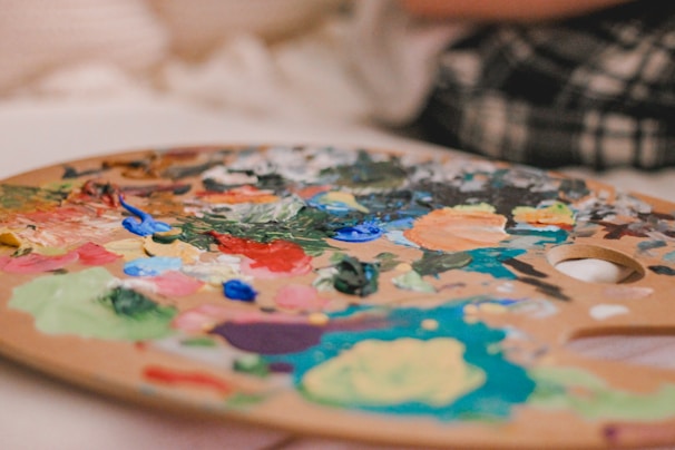 An artist's palette with vibrant colors and unique materials like coffee and wine.