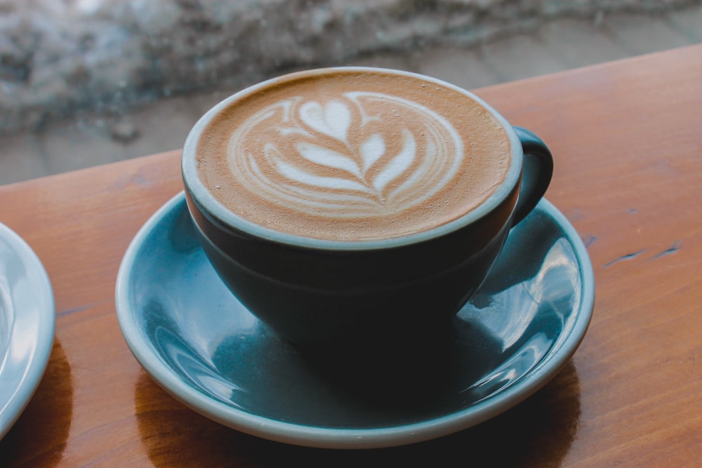 black ceramic cup with saucer on brown wooden table