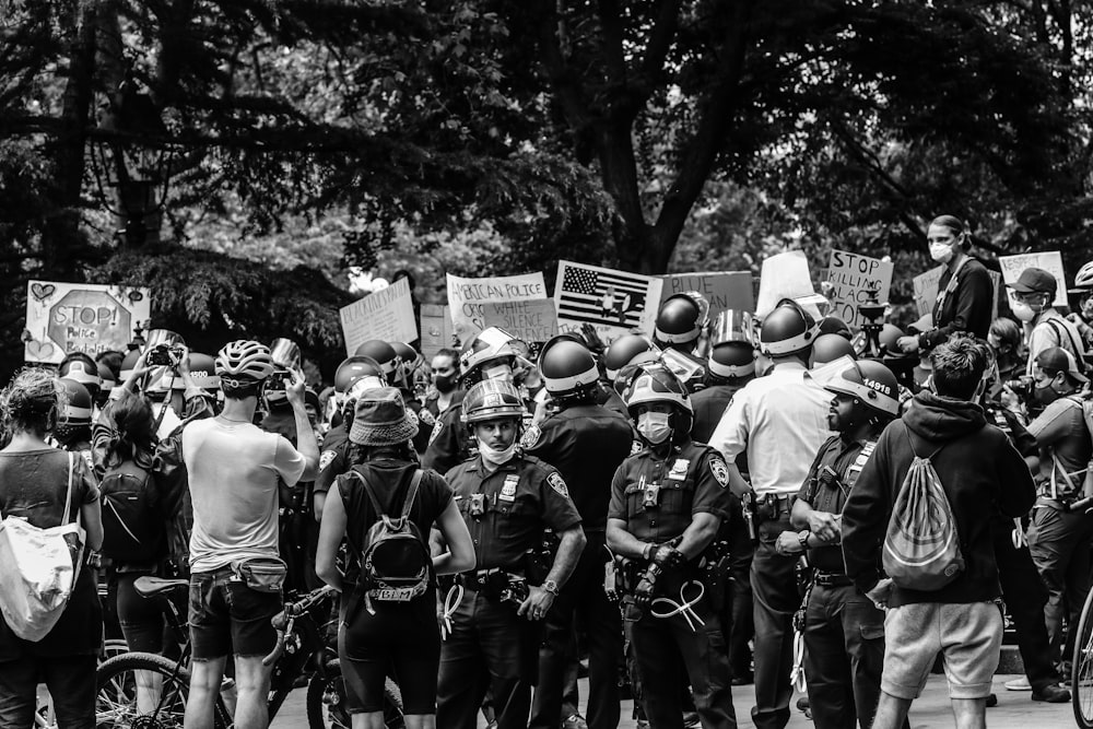 Photo en niveaux de gris de personnes dans un champ avec des arbres au loin