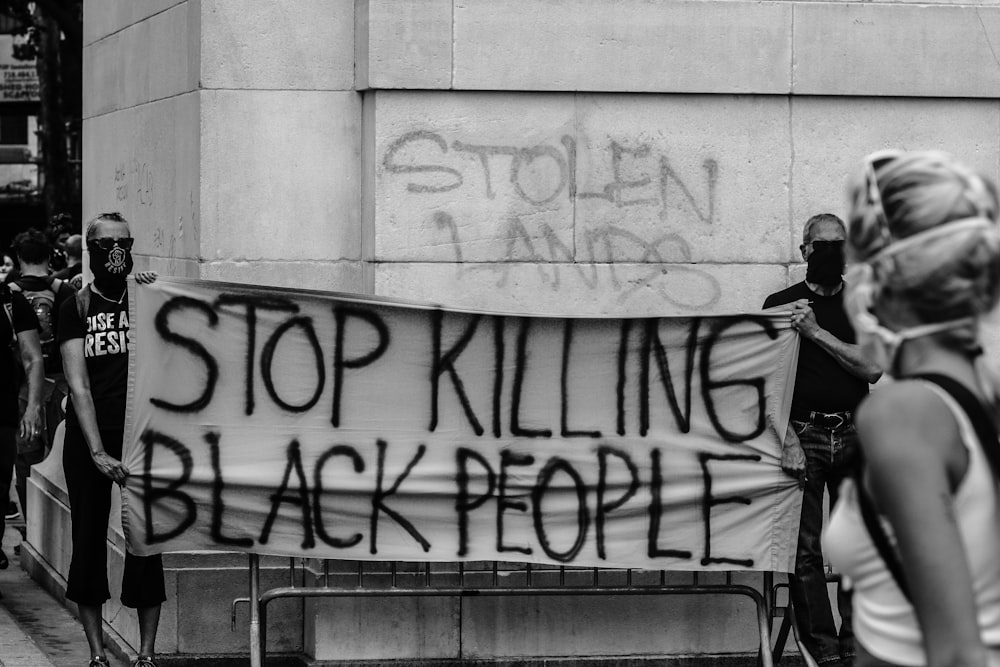 Mann in schwarzer Jacke steht an der Wand mit Graffiti
