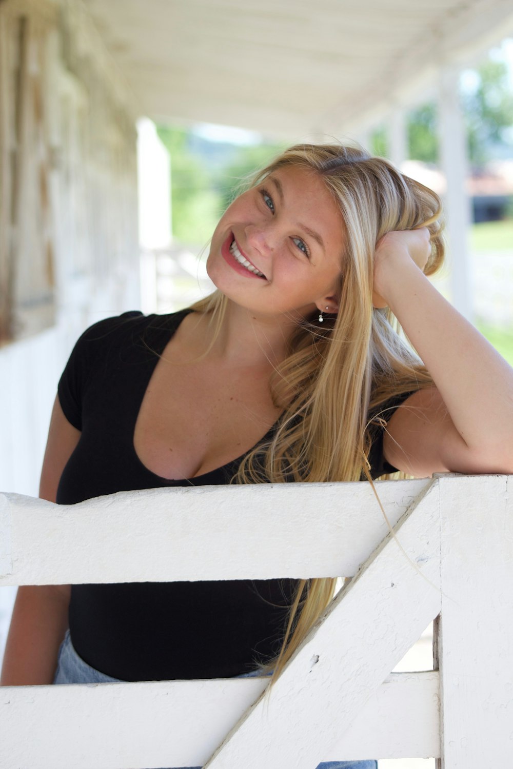 woman in black tank top leaning on white wooden fence during daytime