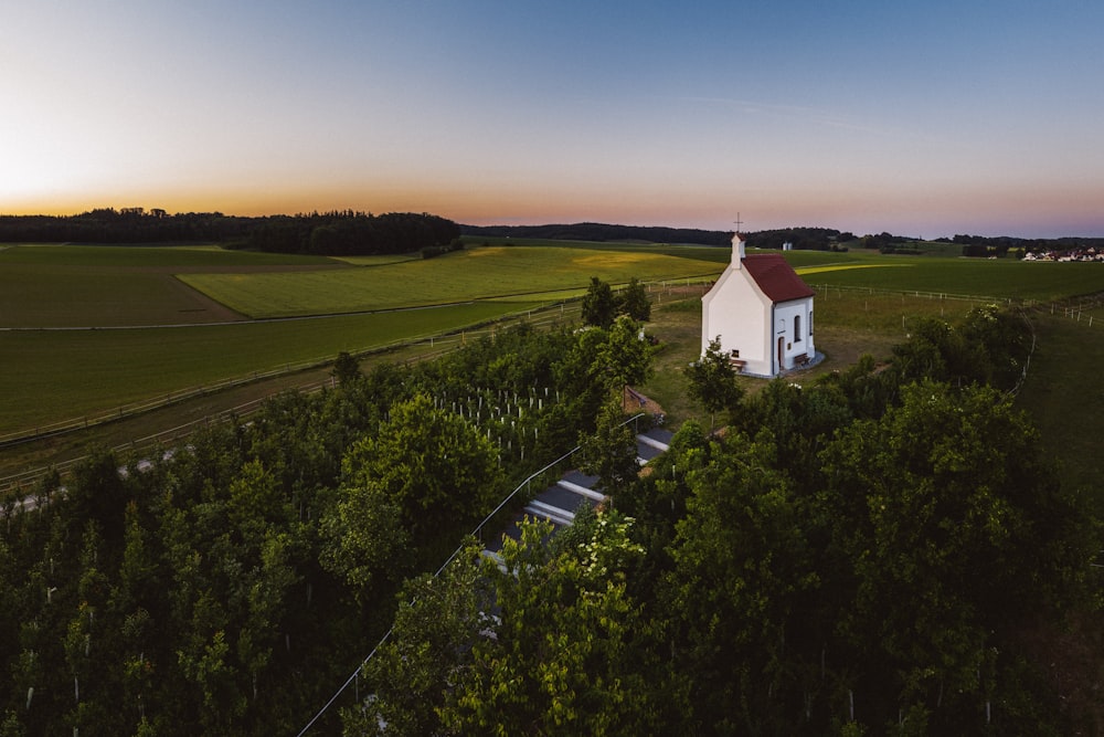 Casa blanca y roja en campo de hierba verde bajo cielo azul durante el día