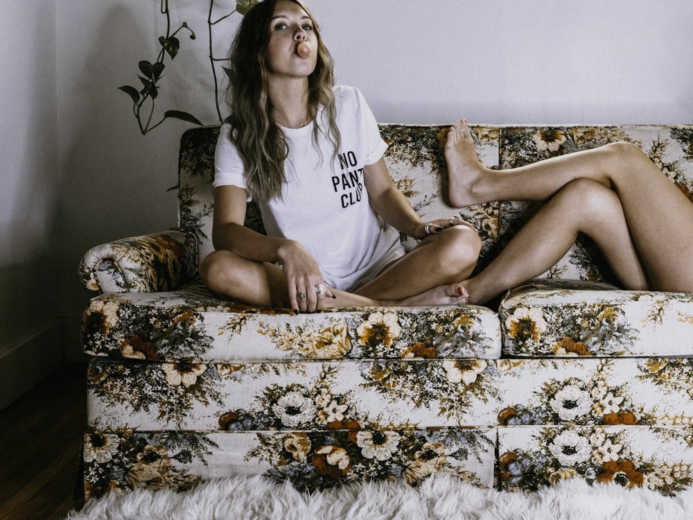 woman in white t-shirt sitting on brown floral sofa