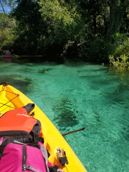 yellow kayak on green body of water during daytime